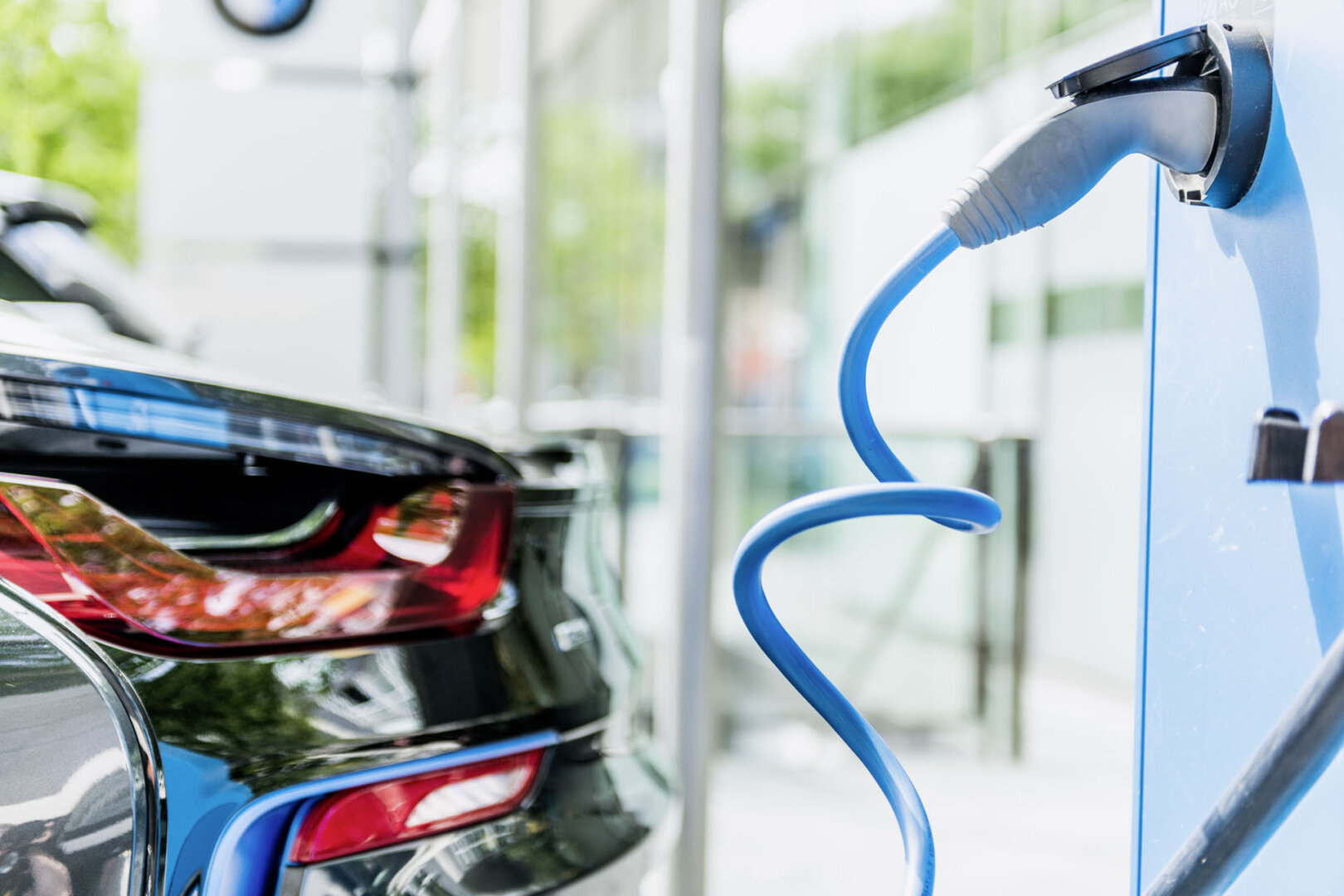 Schwarzes Elektroauto in Nahaufnahme an Ladesäule zum laden angeschlossen