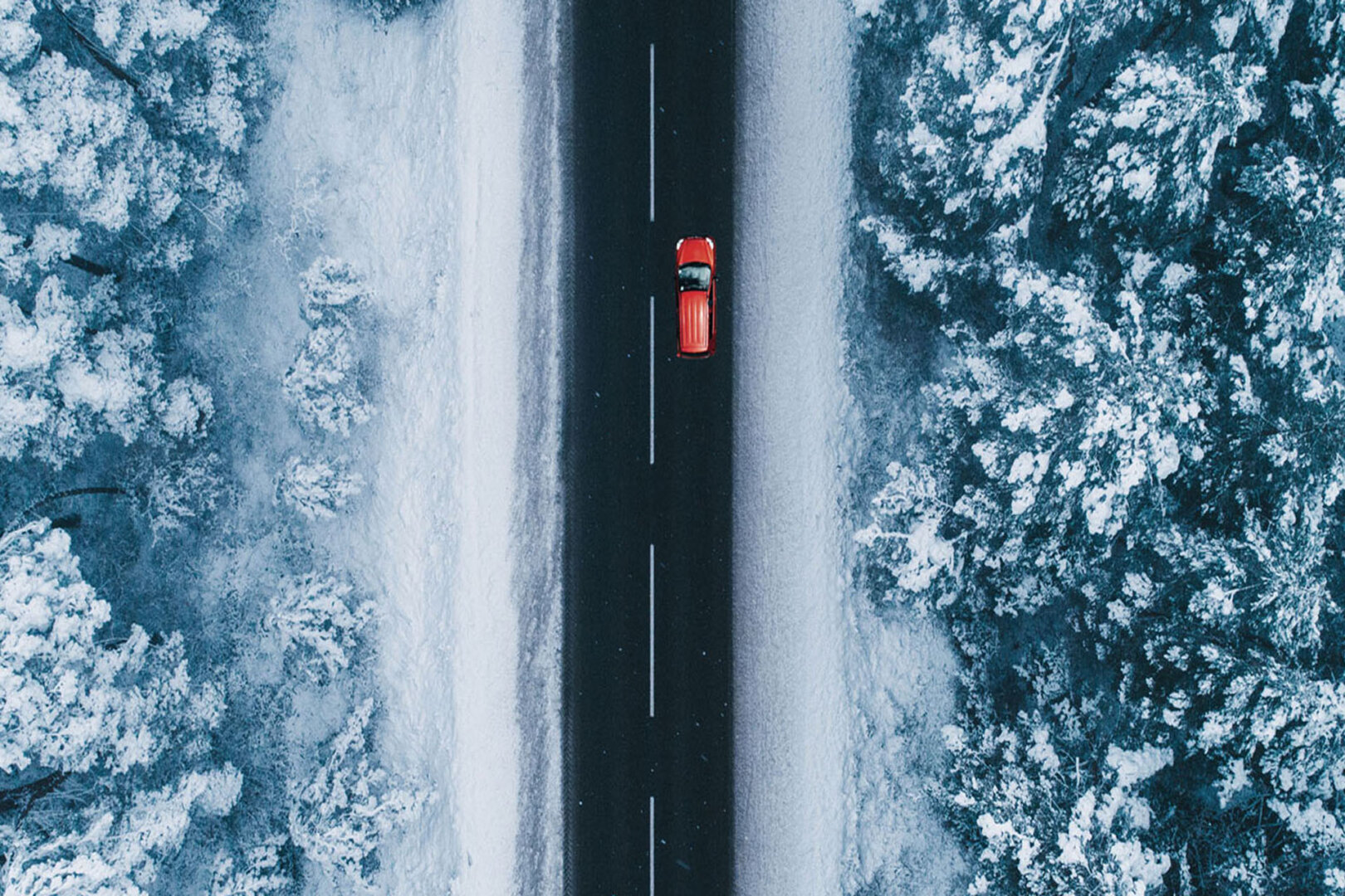 Rotes Elektroauto im Winter: Fahrzeug auf Straße in verschneiter Winterlandschaft