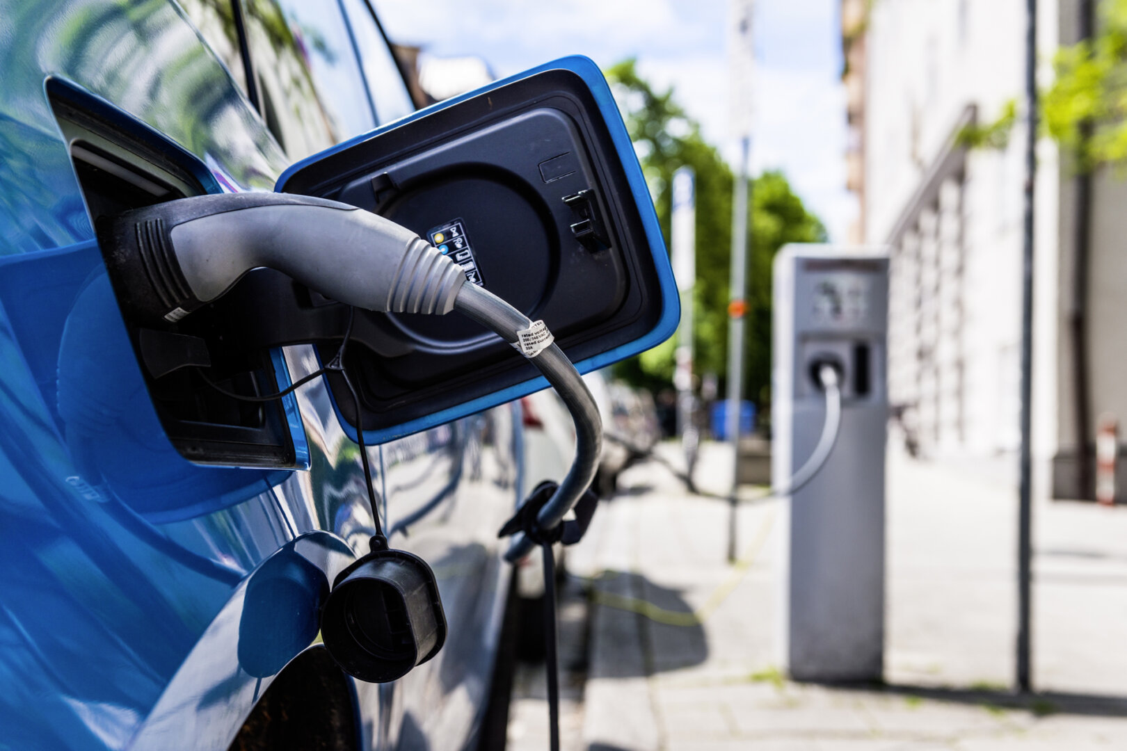 Blaues Elektroauto lädt an einer öffentlichen Ladestationen